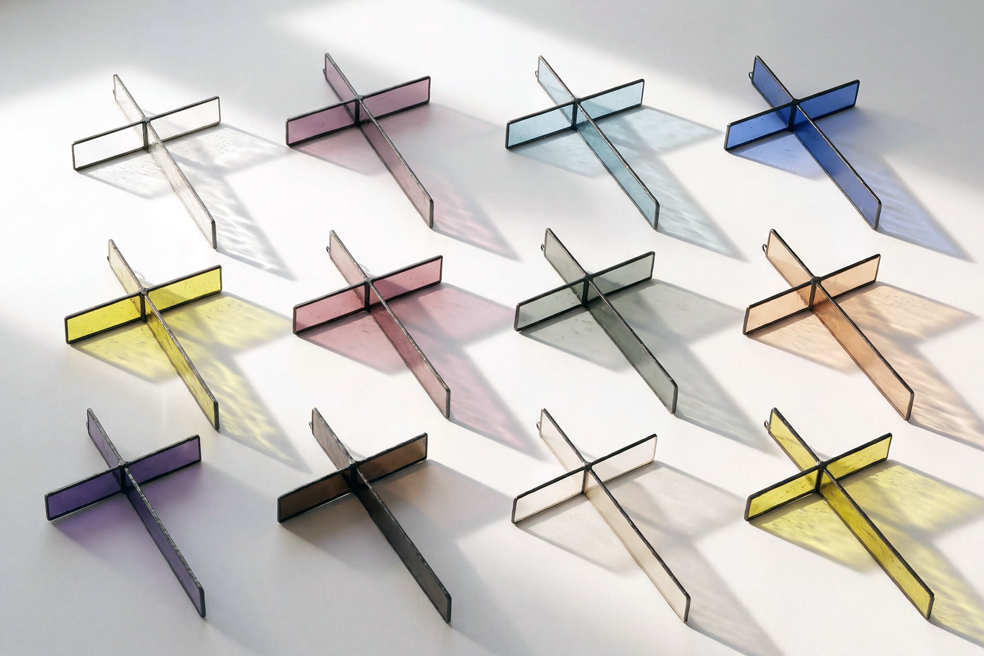 Stained glass crosses on a brightly lit white background, casting pools of bright color.